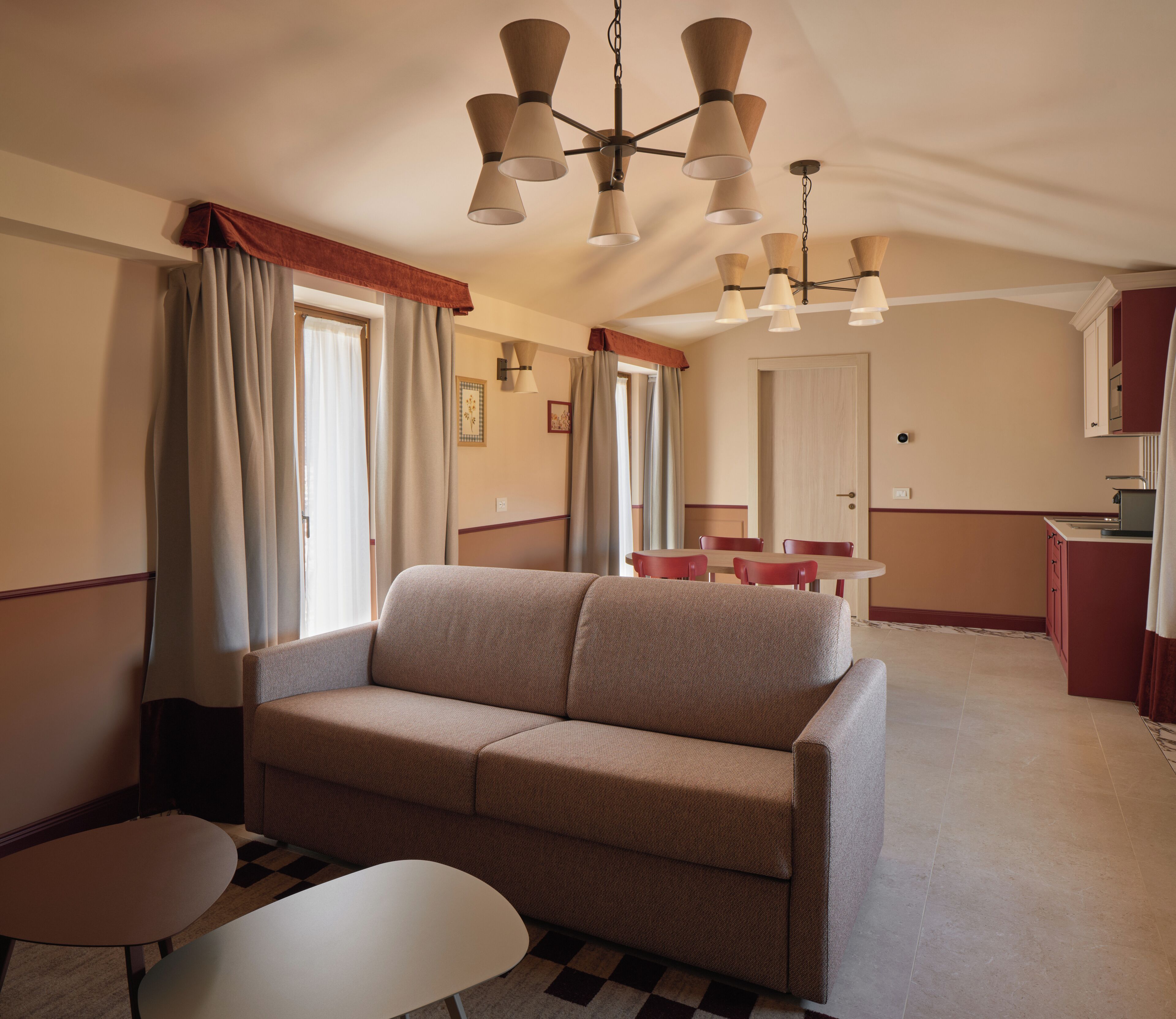 A living room with a sofa, a dining table, and chairs, a kitchen area, and a ceiling fan.