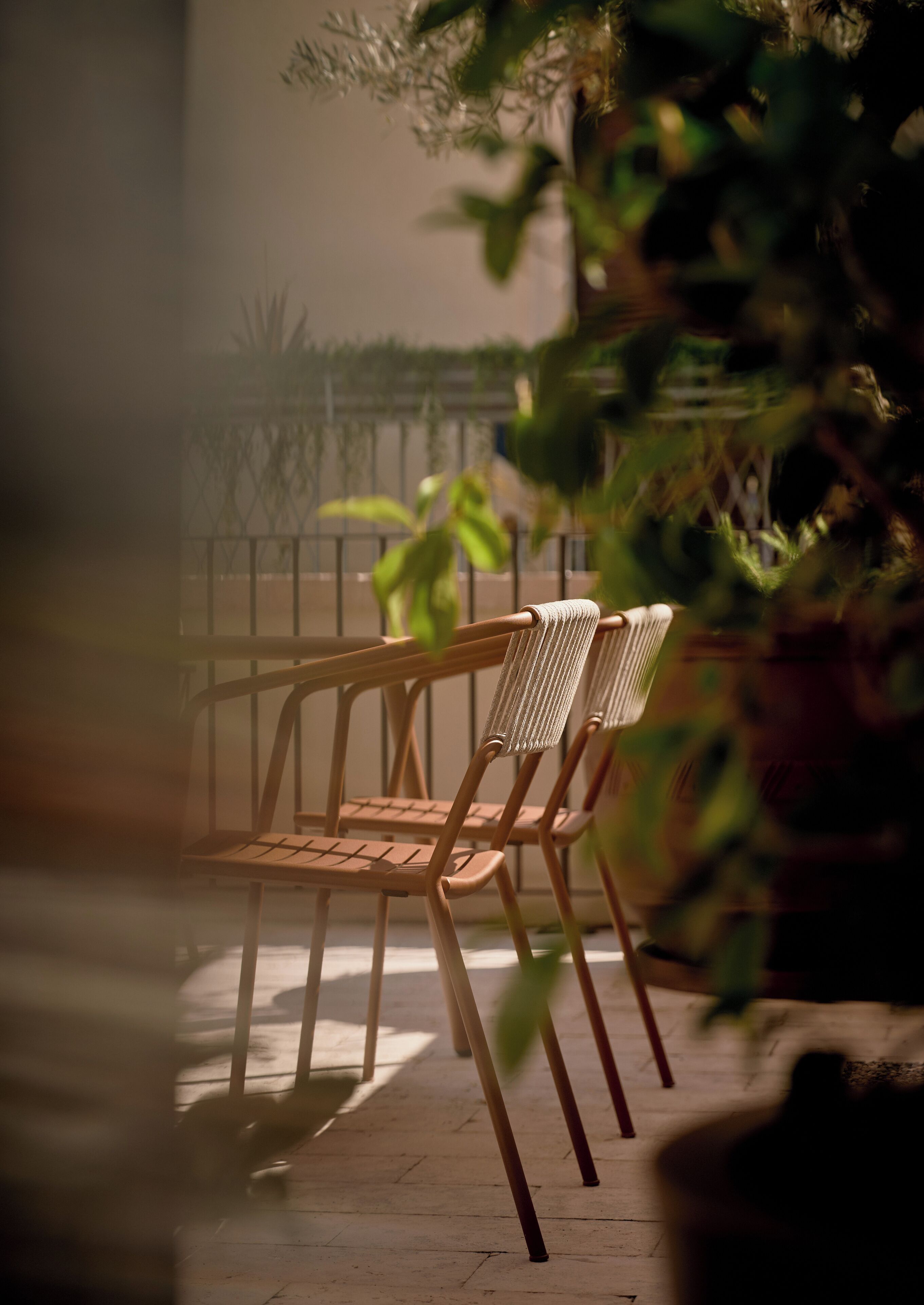 A wooden chair with a woven backrest and metal frame, positioned on a tiled floor.
