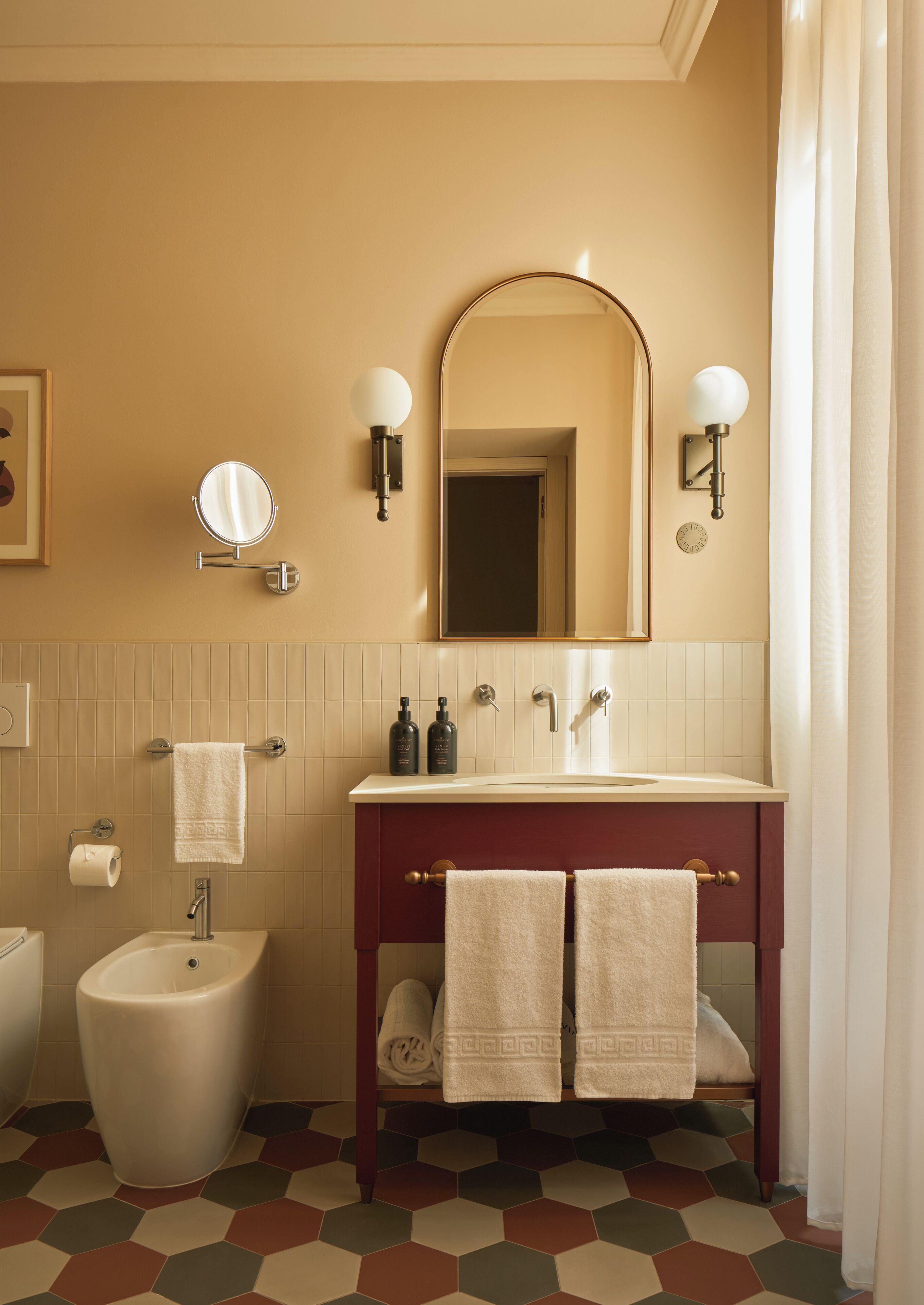 Une salle de bain équipée d’un bidet, d’un lavabo avec deux miroirs et d’un porte-serviettes.