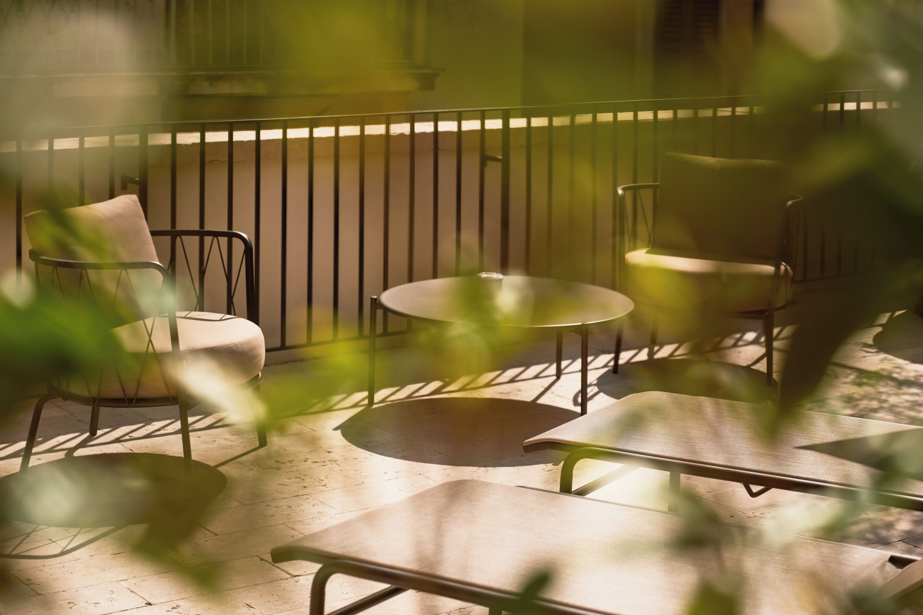 A patio area with metal-framed chairs and tables, a railing, and a building in the background.