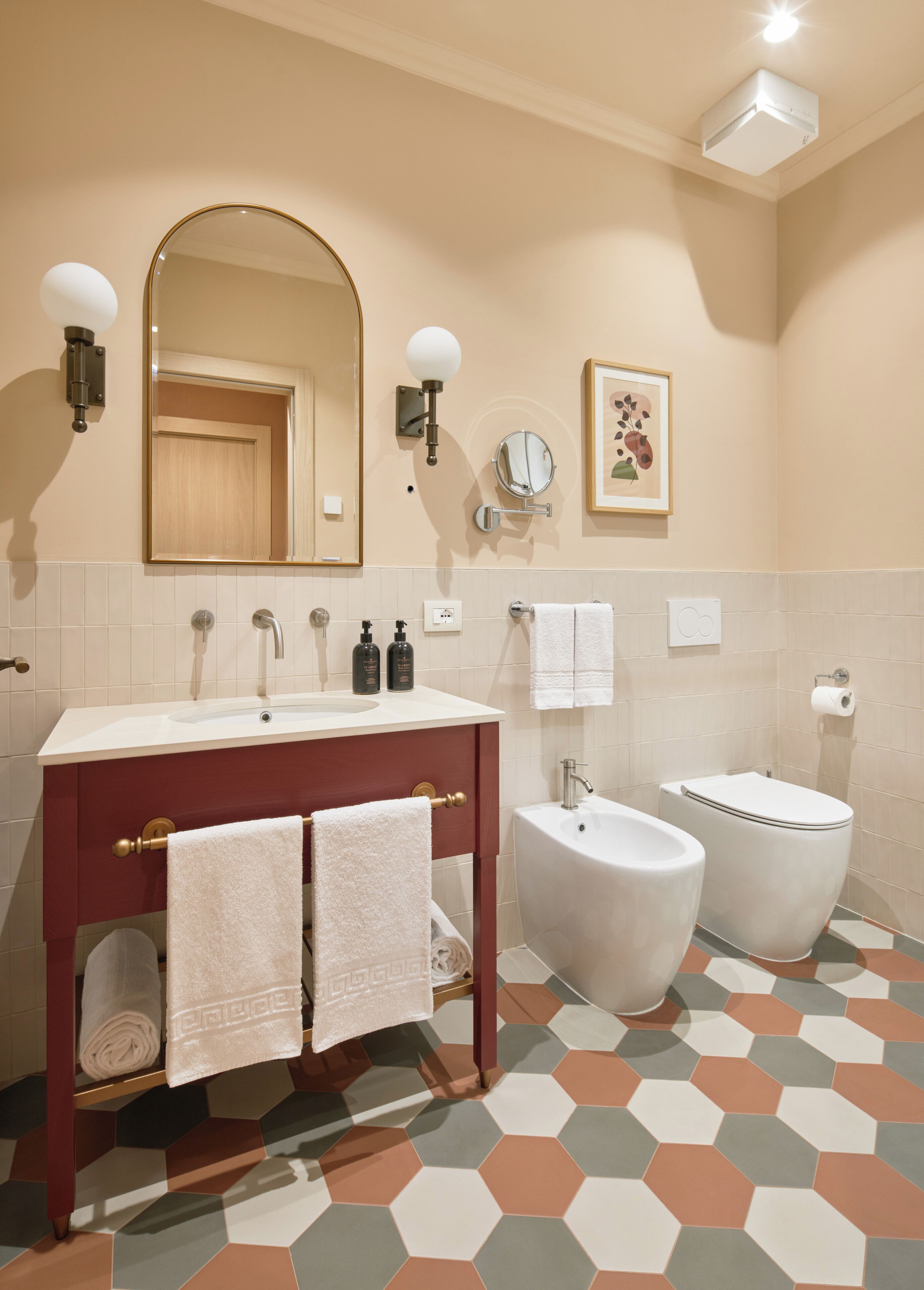 Ein Badezimmer mit Waschtisch, Waschbecken, Spiegel, Handtuchhalter, Toilette und Bidet.
