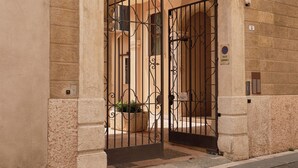 An arched entrance with a wrought iron gate, a stone wall, and a cobblestone street. - Homy Livia Verona (Verona)