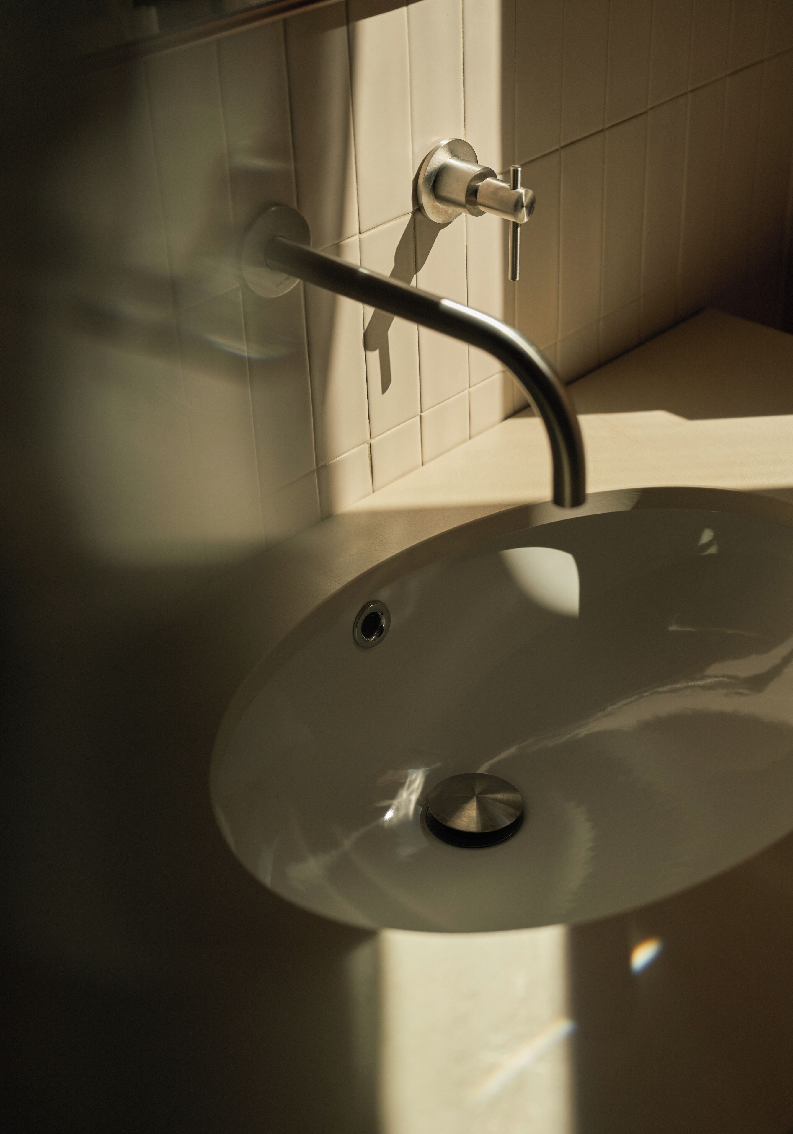Un baño con lavamanos blanco, grifo y cabezal de ducha.