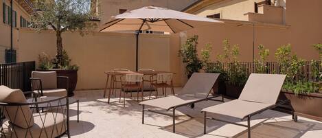 An outdoor patio with lounge chairs, a table, and an umbrella.