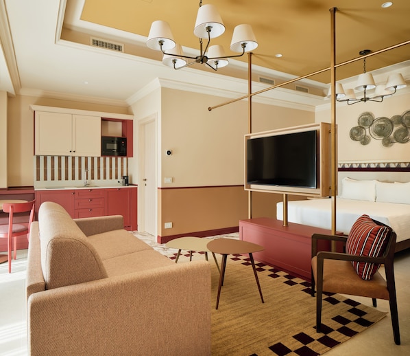 A modern hotel room with a sofa, a chair, a TV, and a kitchenette. - Homy Livia Verona (Verona)