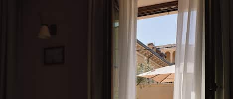 Una habitación con una mesa de comedor y sillas, una ventana con cortinas translúcidas y vista a un patio al aire libre.