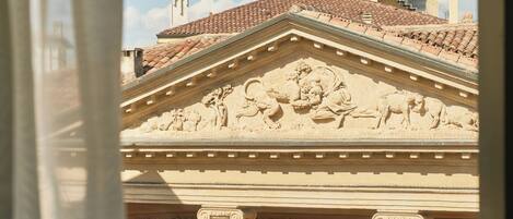 A view of a building with classical architecture, including a pediment with sculptural reliefs and a tiled roof.