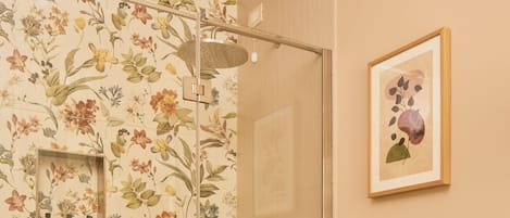 Een badkamer met een douche, toilet en een bloemrijk kunstwerk in een lijst aan de muur.