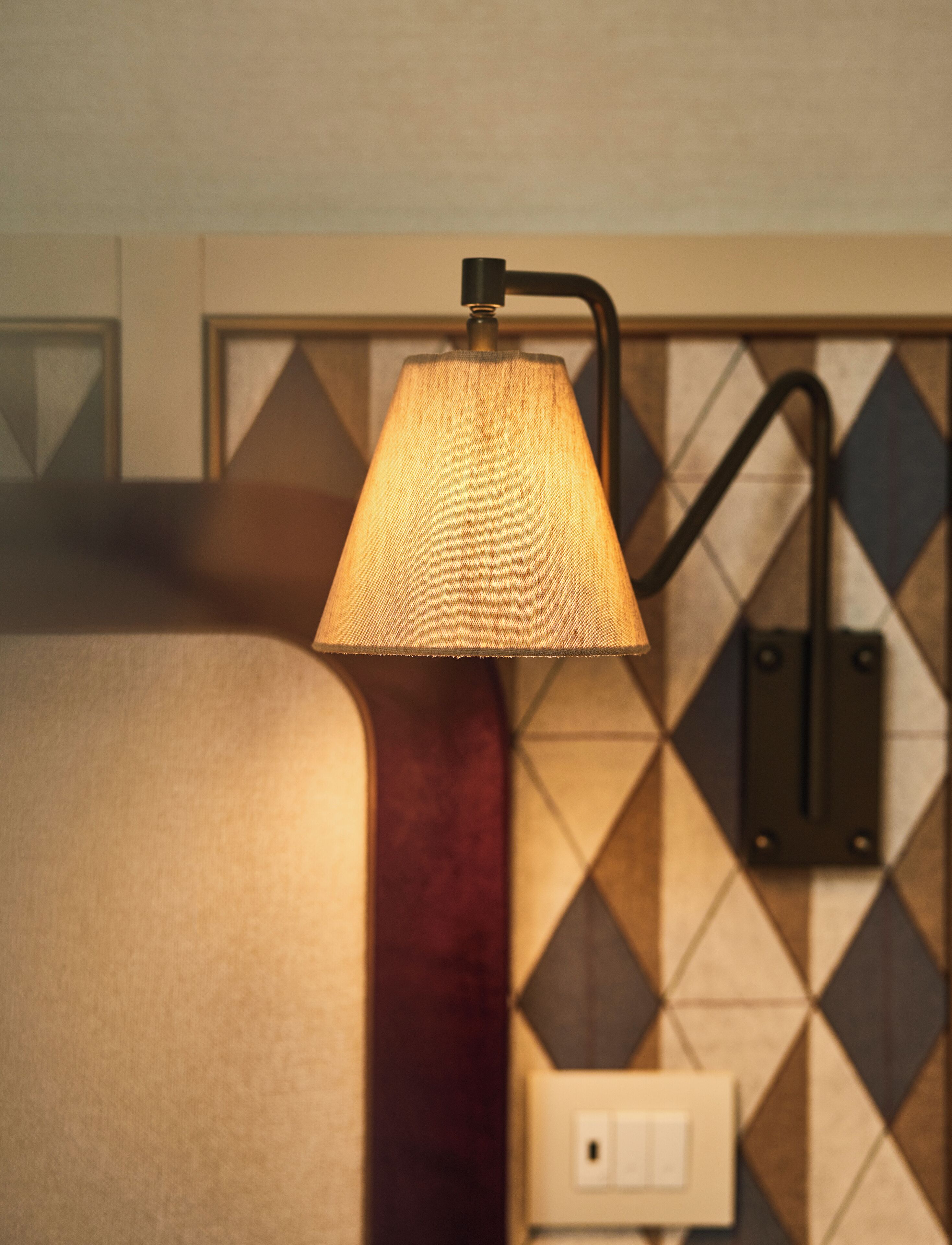 A wall-mounted lamp with a textured shade and a curved arm.