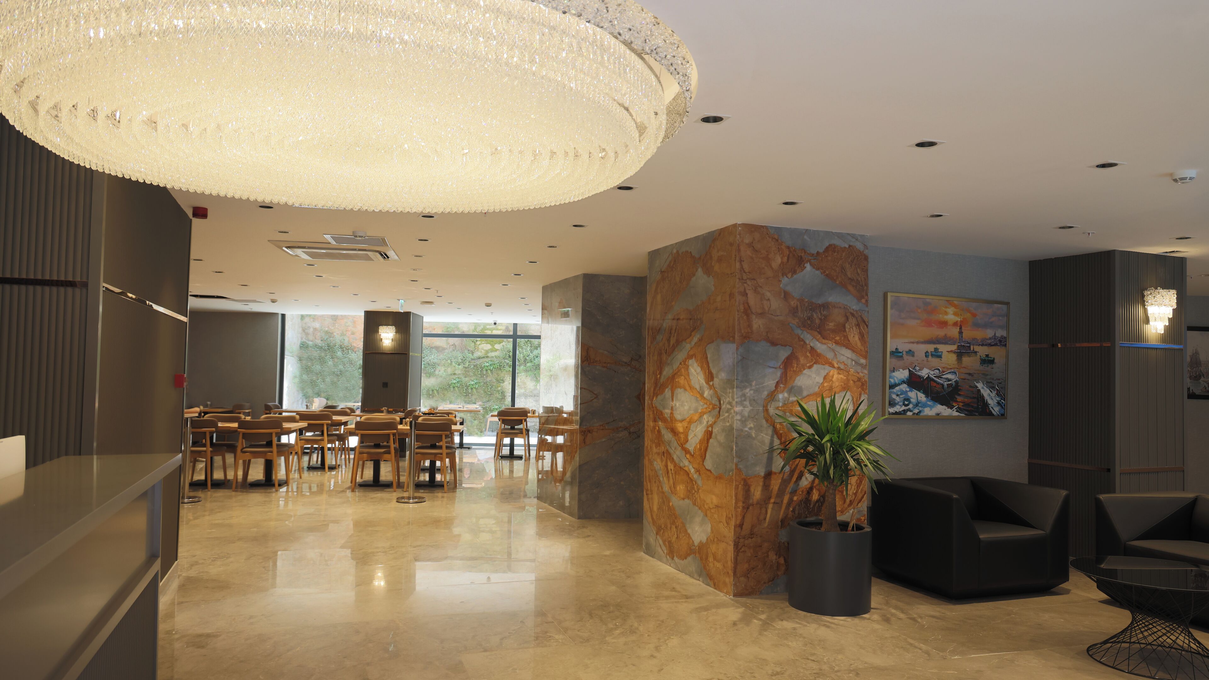 A modern lobby with a large chandelier, seating area, and a mural on the wall.
