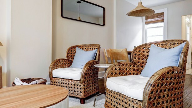 Een woonkamer met rieten meubels, een ronde salontafel en een hanglamp.