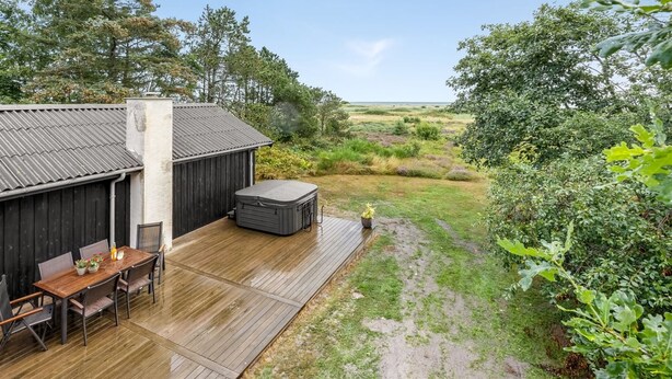 A wooden deck with a table and chairs, a hot tub, and a view of a natural landscape. - "Githe" -  from the sea by Interhome (Hals)