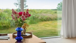 A table with a vase of flowers and a book, a remote control, and a tray. - "Githe" -  from the sea by Interhome (Hals)