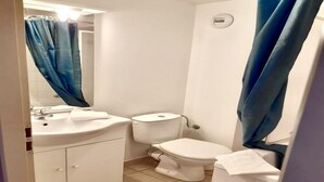 Une salle de bain avec un lavabo blanc, des toilettes et un rideau de douche bleu.