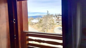 Une vue depuis une fenêtre à cadre en bois, donnant sur un quartier résidentiel avec des maisons et des arbres.