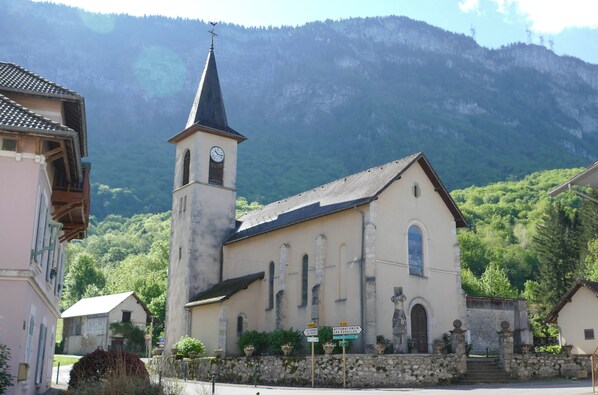 A church with a bell tower, surrounded by stone walls and potted plants.