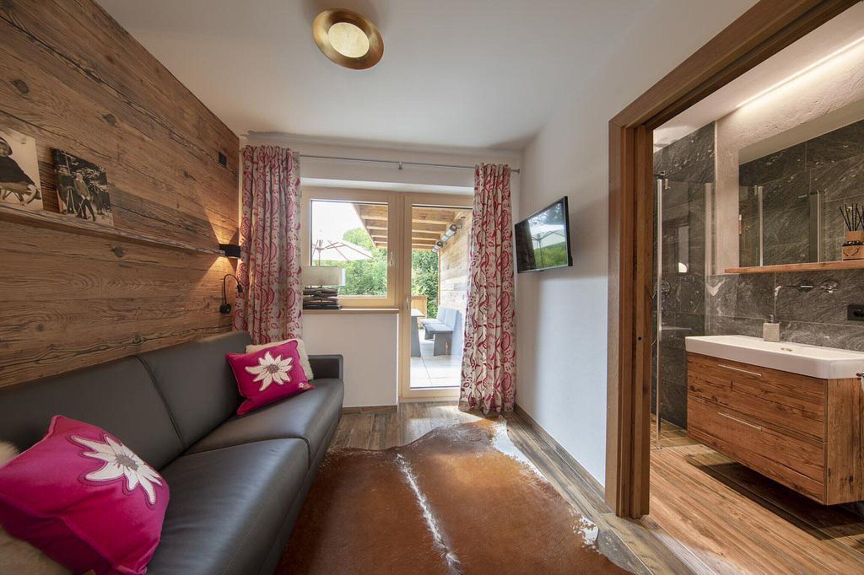 Un baño moderno con tocador de madera, un espejo grande y zona de ducha.