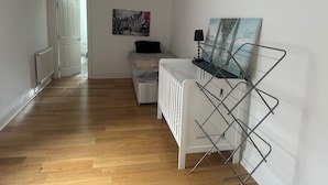 Una stanza con un letto, un termosifone, un quadro e uno stendibiancheria.