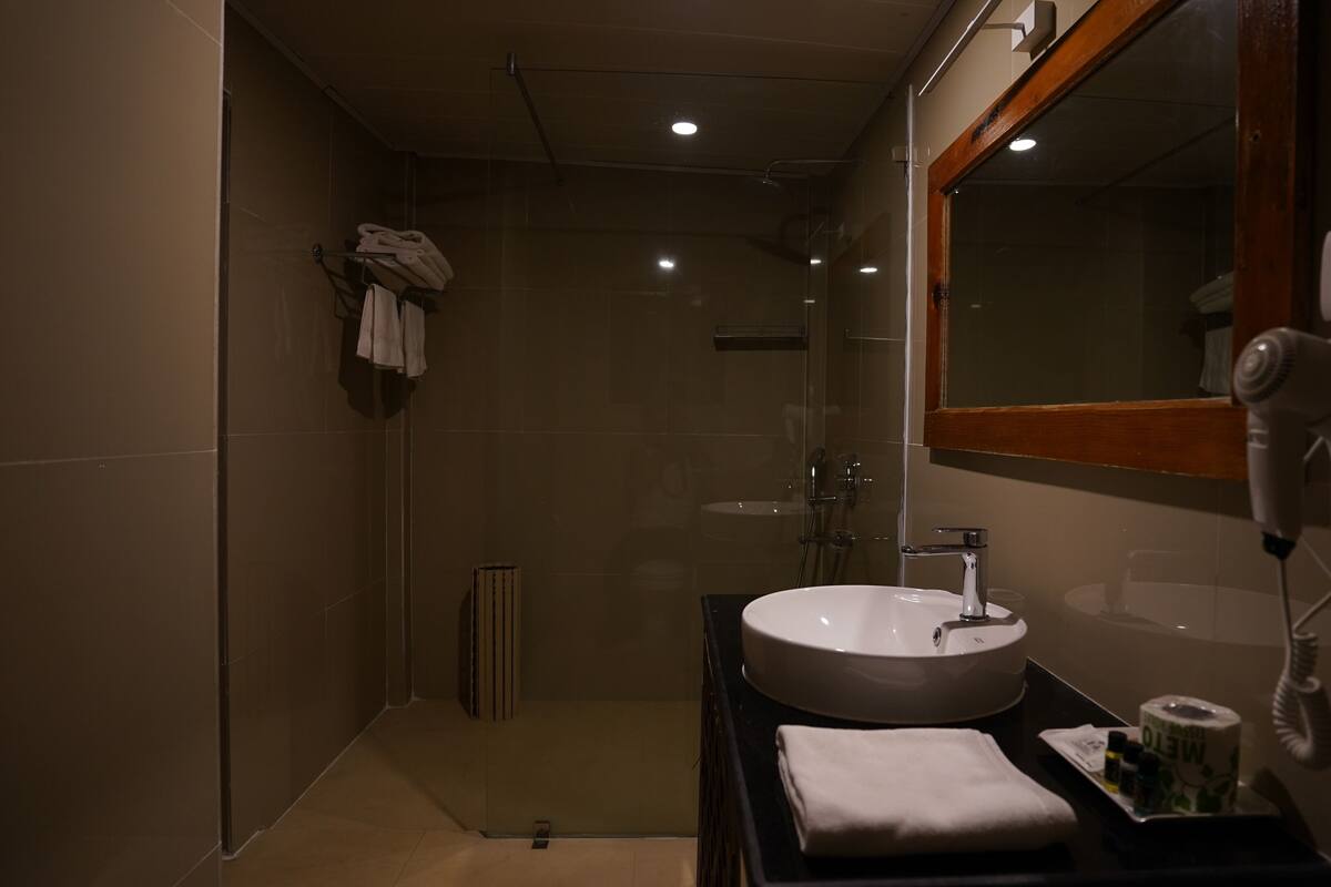 A modern bathroom with a large sink, a mirror, a hairdryer, and a towel rack.