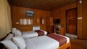 Una habitación de madera con una cama, un escritorio, una silla, un televisor y un cuadro en la pared.