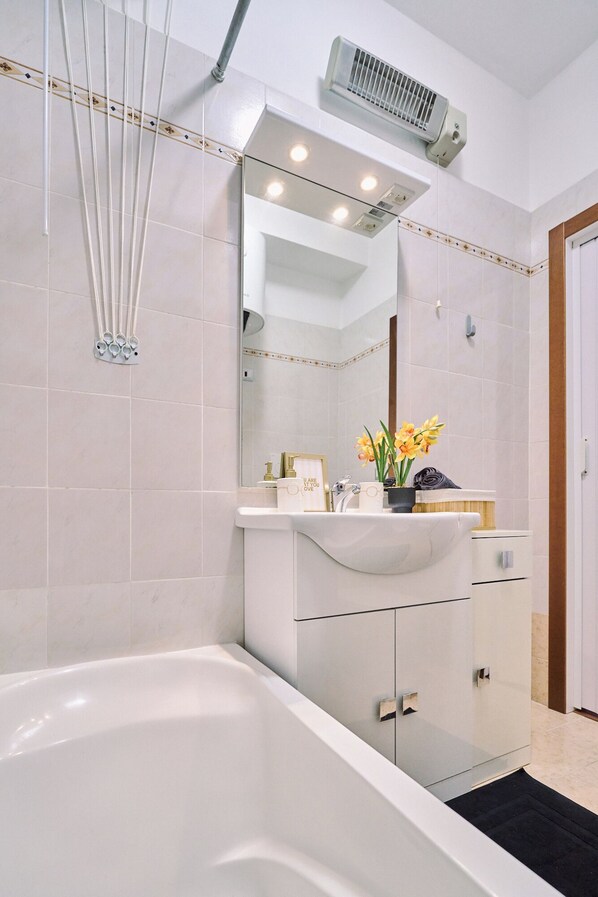 A modern bathroom with a bathtub, a vanity with a mirror, and a towel rack.