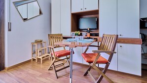 A dining area with a wooden table, two chairs, a small side table, and a mirror on the wall. - Lake Maggiore - Elegant Apartment with Pool (Euroville)