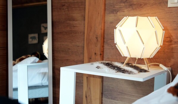 A modern room with a wooden wall, a white bedside table, and a unique hexagonal lamp. - La Sapiniere (Saint-Lary-Soulan)