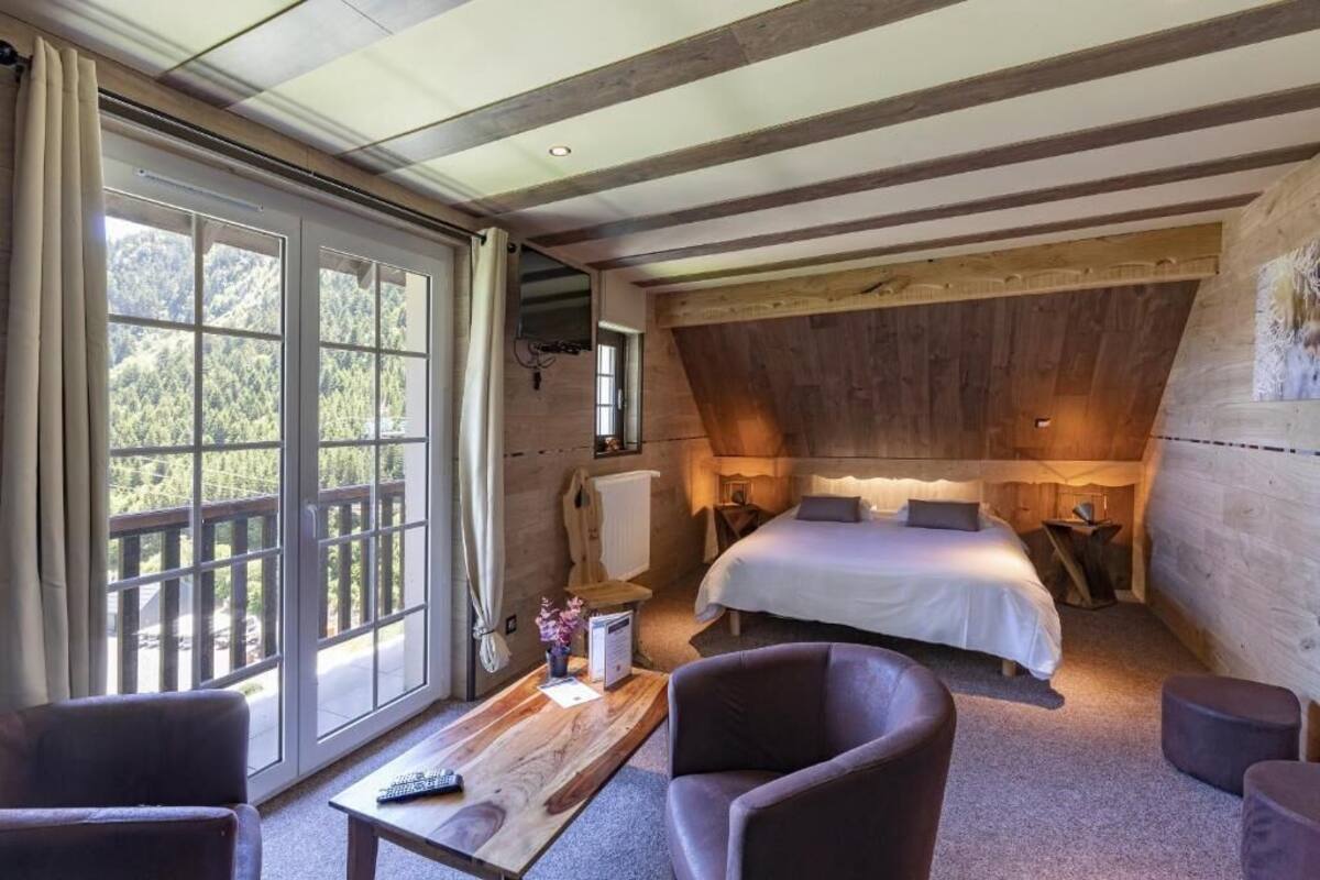 Um quarto aconchegante com uma cama grande, teto de madeira e vista para o exterior através de uma porta de correr.
