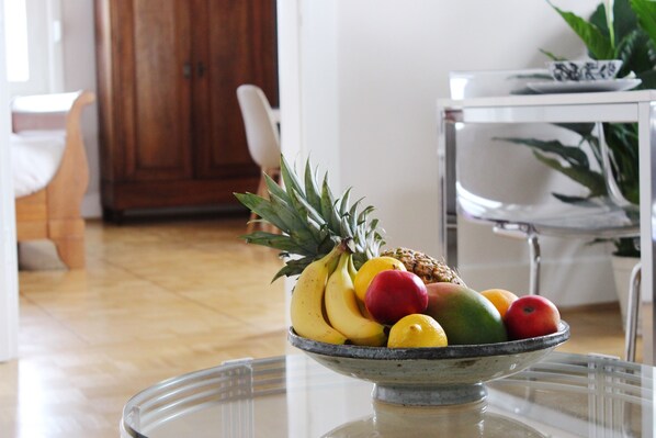 A bowl of fruit on a glass table in a room with wooden flooring and white furniture. - 90 m² family-friendly apartment (Bad Soden am Taunus)