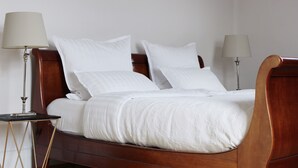 A neatly made bed with white linens and pillows, flanked by two bedside tables with lamps, in a room with plain walls. - 90 sqm apartment suitable for family (Bad Soden am Taunus)