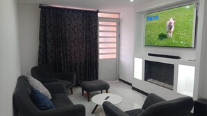 A modern living room with a flat-screen TV mounted on the wall, a fireplace, and a sofa set. - Comfortable house to rest in Paipa, excellent location. (Paipa)
