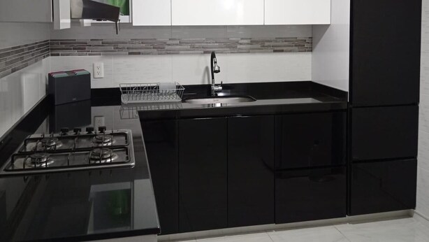 A modern kitchen with black and white cabinetry, a gas stove, a sink, and a green water dispenser. - Comfortable house to rest in Paipa, excellent location. (Paipa)