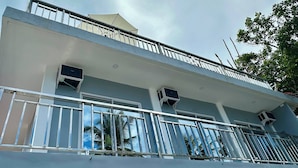 Ein mehrgeschossiges Gebäude mit Balkon, Klimaanlagen und blauem Himmel.