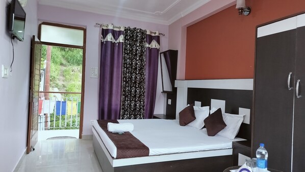 A bedroom with a bed, a wardrobe, a television, and a window with curtains. - Hotel Adventure Inn 20 Metre from Swimming Pool (Dharamshala)