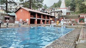 A swimming pool with a building in the background. - Hotel Adventure Inn 20 Metre from Swimming Pool (Dharamshala)