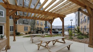 An outdoor patio area with wooden picnic tables and a pergola structure. - Simplicity  1103 I Spacious 1Bd/1bth Apartment (San Antonio)