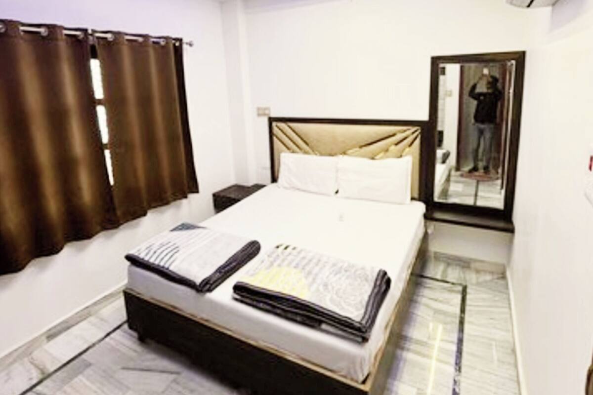 A modern bedroom with a bed, curtains, a ceiling fan, and an air conditioning unit.