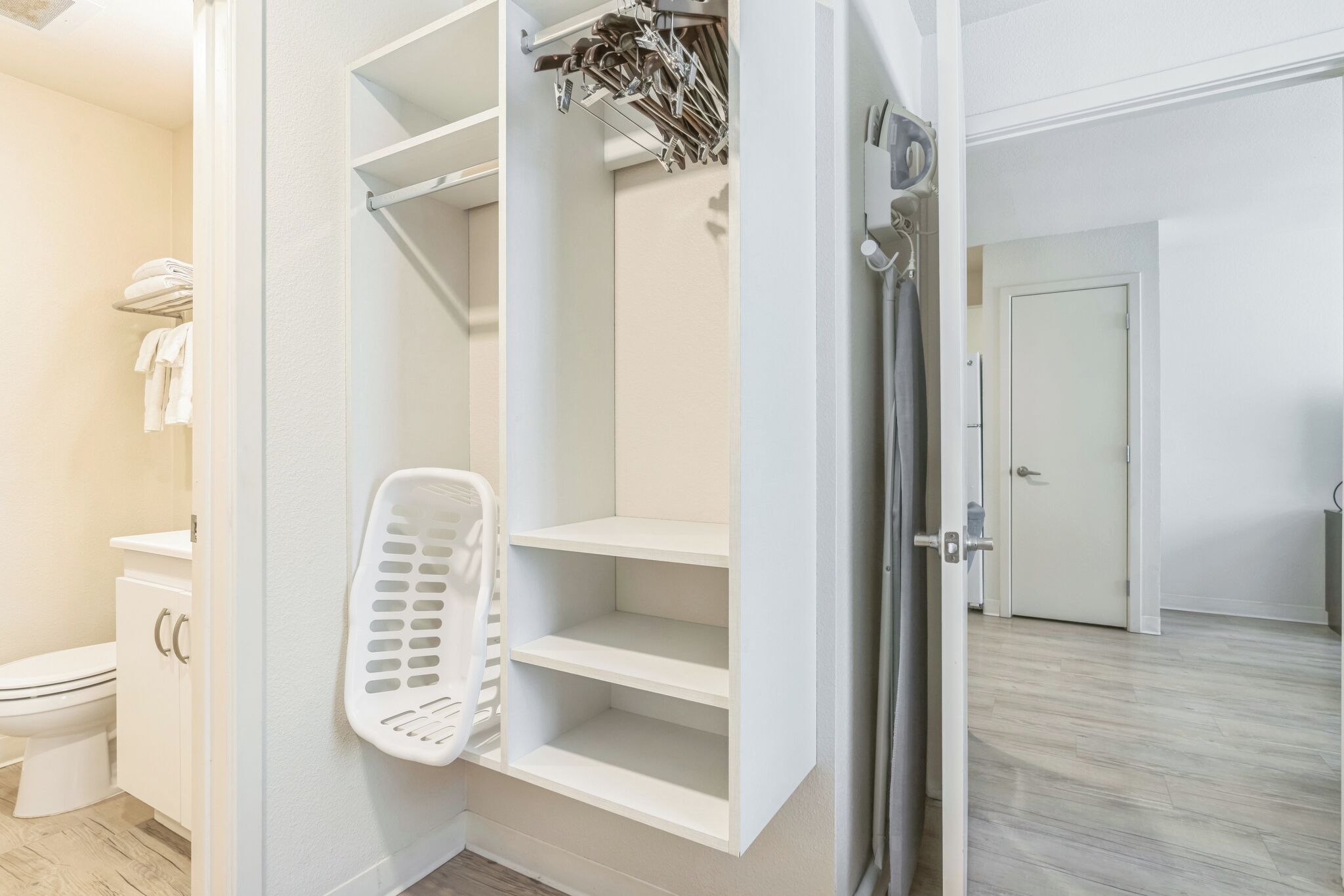 Une salle de bain comprenant des toilettes, un panier à linge blanc et un espace douche.