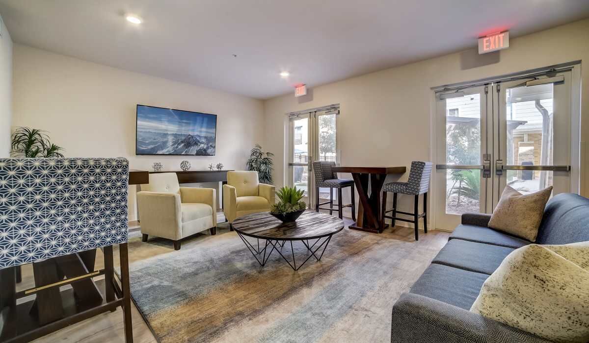 A modern hotel lobby with a sofa, chairs, a coffee table, and a painting on the wall.