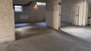 A room with concrete walls, a sloped ceiling, and a door. There is a window with a view of the outside. - 002 Moderno Trilocale Pinzolo (Pinzolo)