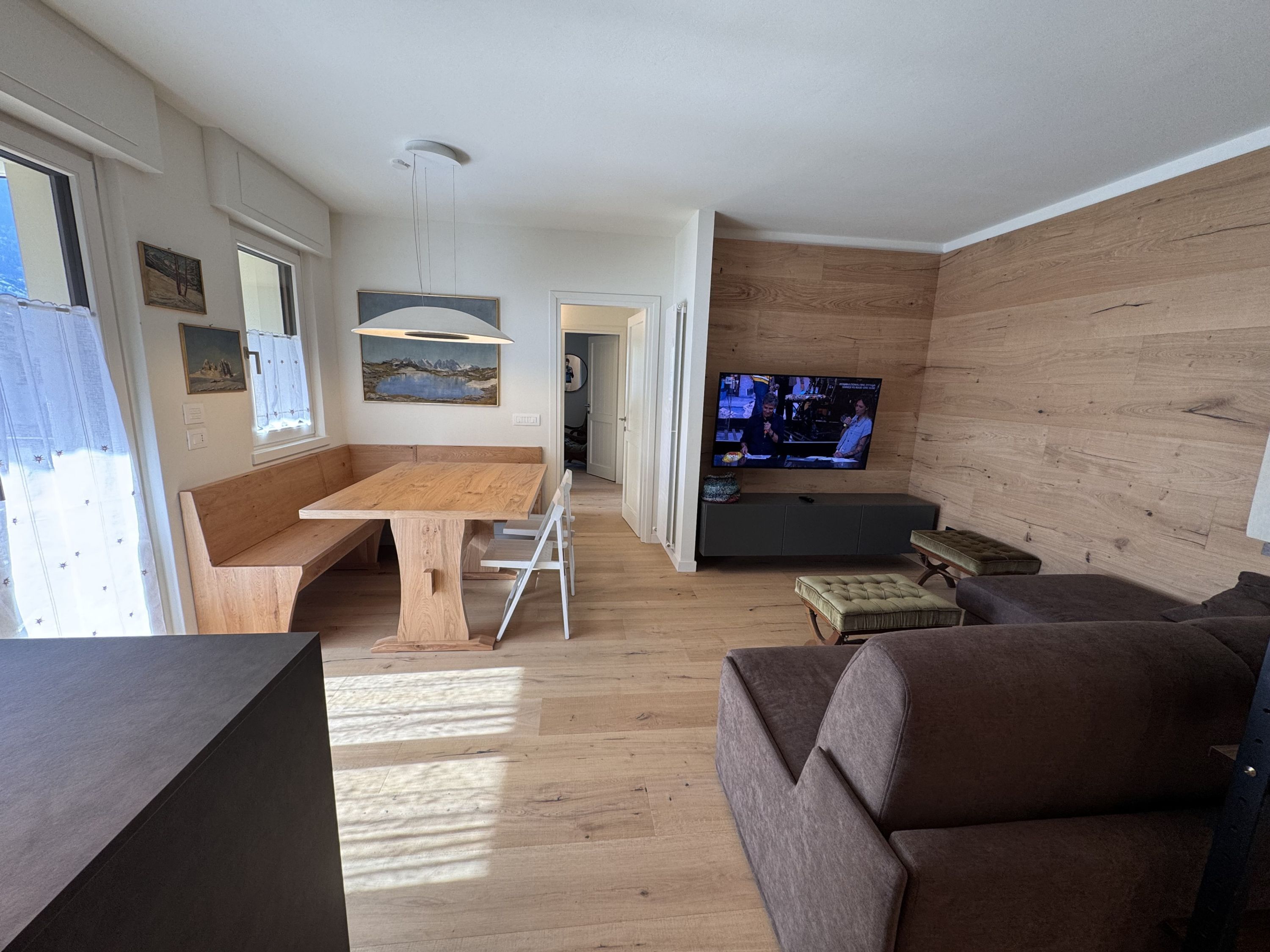 A modern living room with a wooden dining table, a sofa, and a television.
