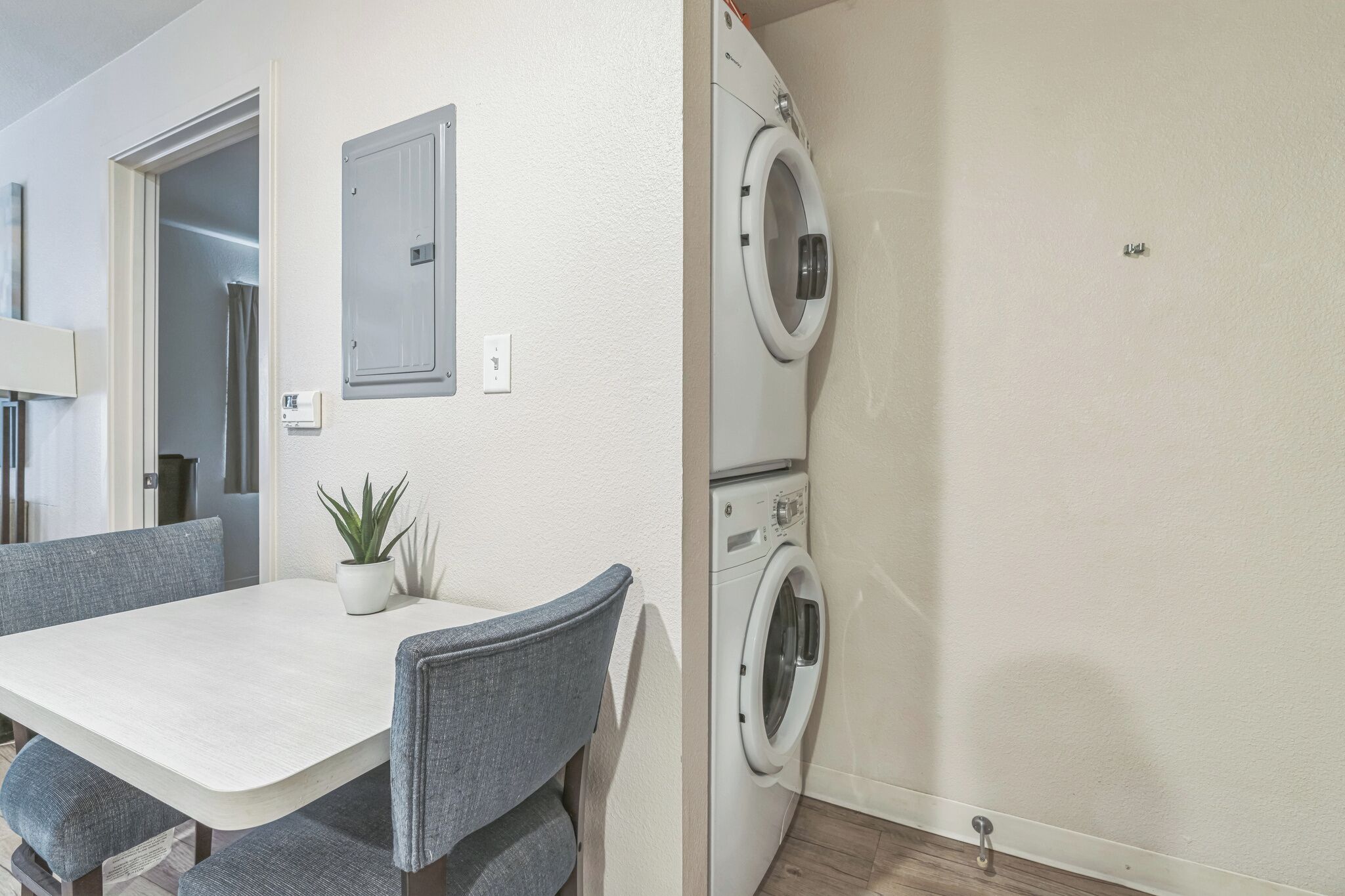 A compact living space with a dining area featuring a table and chairs, a built-in washing machine, and a small potted plant.