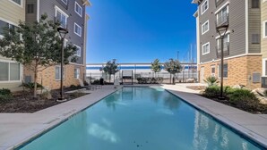 A swimming pool with a clear blue water surface, surrounded by a paved walkway and trees. - Stunning 1Bd/1Bth I Properties by Preston (San Antonio)