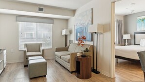 A modern hotel room with a sofa, ottoman, bedside tables, lamps, and a bed. - Stunning 1Bd/1Bth I Properties by Preston (San Antonio)