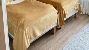 A room with two beds, wooden panel walls, white curtains, and a wooden floor. - Kotimaailma KotikaksioKirkkok saunalla (Lahti)