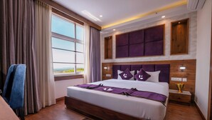 A modern hotel room with a large bed, wooden headboard, and a view of the outdoors. - purple leaf (Bhubaneshwar)