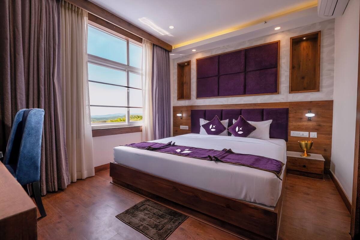 Ein modernes Hotelzimmer mit einem großen Bett, einem Holzkopfstück und Blick ins Freie.