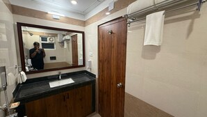 A bathroom with a wooden vanity, a large mirror, a towel rack, and a shower area. - purple leaf (Bhubaneshwar)