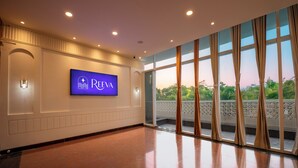 A spacious lobby with a large TV screen displaying the REVEA logo, a tiled floor, and large windows with curtains. - purple leaf (Bhubaneshwar)