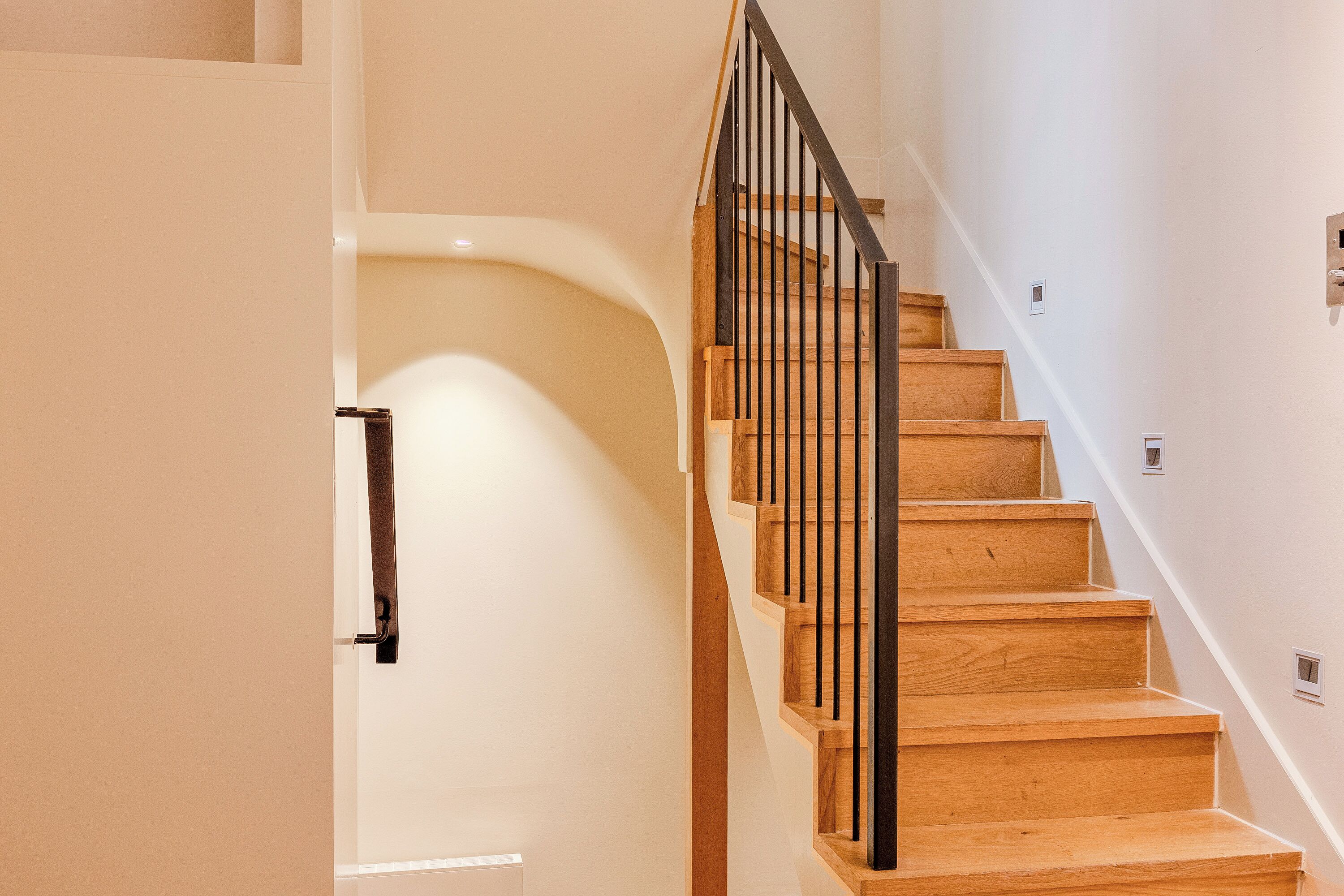A staircase with wooden steps and a metal railing, leading to an upper floor.